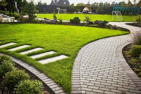 Landschaftsgestaltung des Gartens. Pfad, der sich durch einen Rasen mit grünem Gras und Gehwegplatten schlängelt